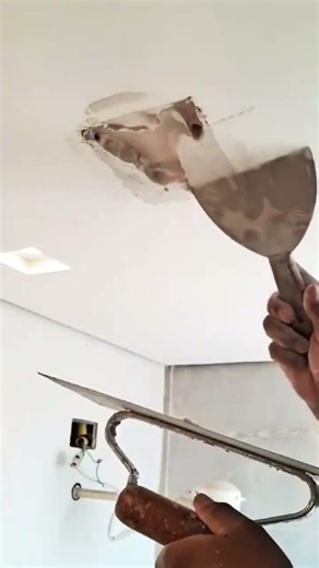 The plasterer who works with plaster is demonstrating how to renovate and cover a hole in the cei...