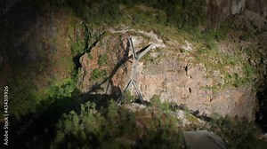 A tilt-shift video of the new viewing platform at the breathtaking Voringfoseen waterfall. An intricate metal structure hanging above the deep ravine. People standing on a platform admiring the view.
