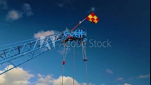 The pulley system of main boom tip sheave on the end of the jib of a blue luffing construction crane. Flag is billowing in the wind. Camera orbits in medium close-up.