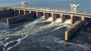 Hydroelectric dam or hydro power station at water reservoir, aerial view from drone. Draining water through gate, hydropower