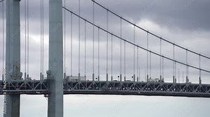 Telephoto view of small car and truck traffic traversing Throgs Neck Bridge between the Bronx and Queens in New York City with grey cloudy sky and seagull.