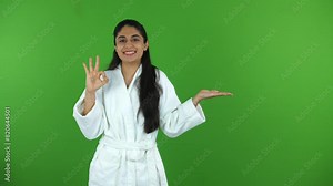 Green screen shot of a beautiful Indian model shooting for a skin care product - ad space copy space. Young female in a bathrobe praising a cosmetics product - green screen shoot chroma shoot he...