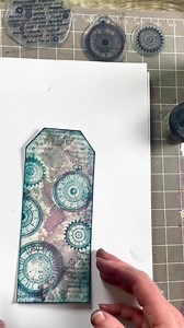 5.9K views · 370 reactions | How to create a beautiful Tag using Gel press and sprays  Watch todays quick crafts as Tracey uses a technique using mica mist sprays with a Gel Press In this craft, Tracey also uses: distress Glaze to protect the clockwork stamps from smudging from the mica Sprays, she also uses midnight blue elements ink and a touch of twilight to surround the card ✨ | Lavinia Stamps | Facebook