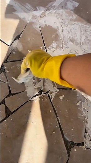 Scraping the broken tile surface clean to remove old grout