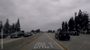 Hyper lapse of a POV of driving down a multi-lane highway on a cloudy day with lots of traffic