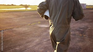 Fighter Pilot or Combat Pilot Holding Flying Helmet While Walking at Sunset in the Air Base. Slow Motion. 4K Resolution.