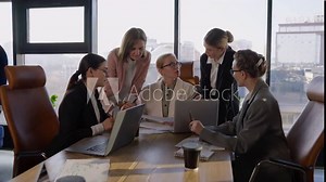 Side view of a confident middle-aged blonde girl in a white business suit communicates with her colleagues during a meeting and listens to their suggestions and ideas while working in the office