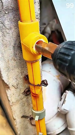 Hand connects white PVC pipe to yellow wall fitting