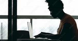 One young black woman using laptop computer in silhouette. African American person engaged with modern technology typing and working from home