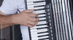 Man plays accordion. Artist performs and plays musical instrument. Tradition and celebration. Caucasian man plays accordion musical instrument and with right hand presses keyboard buttons
