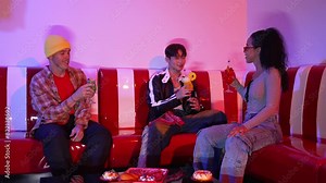 Multicultural friend clinking glass to celebrate their team work at home party with neon light. Professional diverse people with stylish fashion holding colorful juice and clink together. Regalement.