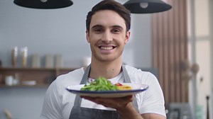 Smiling chef man holding plate with salad in the kitchen | Free Stock Video Footage