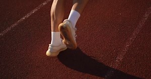 Slow Motion Closeup of the Male Legs of an Unrecognizable Athlete While Running on the Running Track