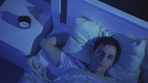 Man staring up at the ceiling struggling to get to sleep - Free Stock Video