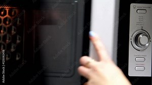 Young Woman Warms Meat Pie in the Microwave Oven