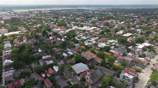 Panoramic Aerial view of downtown skyline church steeple landscapes of coastal Charleston, South Carolina showcasing lowcountry metropolitan neighborhood scenery - 4K Drone