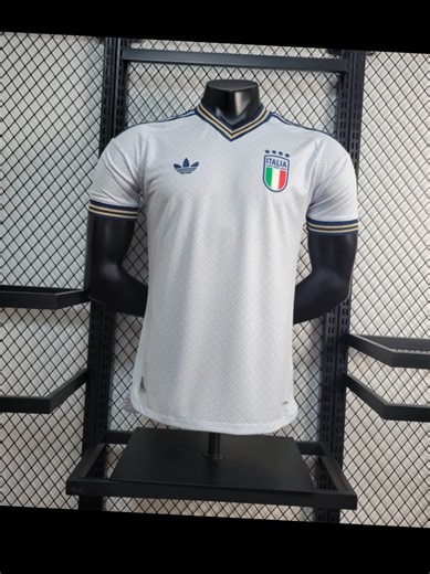 Italy’s 2026 World Cup Away Player Version jersey is a timeless masterpiece for the Azzurri faithful 🇮🇹 This crisp white kit features navy and gold trim on the V-neck and cuffs, paired with a subtle geometric pattern that nods to Italian design heritage. The iconic Adidas Trefoil logo, embossed FIGC crest with four stars (for Italy’s World Cup wins!), and Climacool breathable fabric make this pro-level gear – built for the pitch and the stands. Plus, the handwritten “italia” on the back adds a