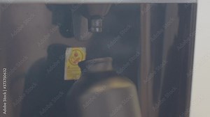 A black water bottle is being filled with water coming out of a water machine.