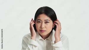 Close-up view of a beautiful asian korean woman looking to the camera as to the mirror standing isolated over white background in the studio