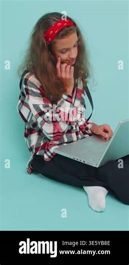 Happy young teenager child girl kid 12 years old works on notebook laptop pc, sends messages, makes online purchases, watching movies. Preteen children isolated sitting on studio blue background Stock Video Footage - Alamy
