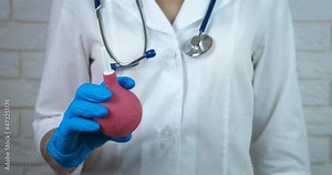 Nurse with medical enema. A view of therapist in medical gloves with an enema in her hands in the room.