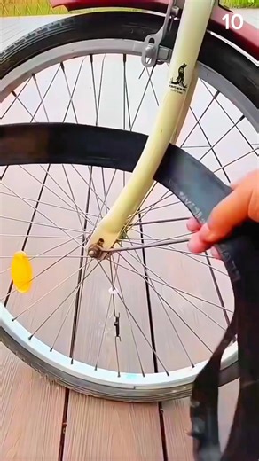 Hand grips deflated tube—front wheel waits as PHOENIX frame steadies repair on wooden deck.