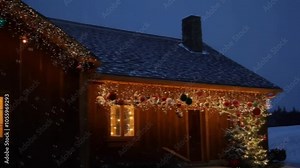 A charming wooden house is festively decorated with twinkling Christmas lights, which illuminate the early evening as gentle snowfall blankets the surroundings. This cozy winter scene captures the ess
