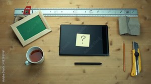 Man putting off sticky note with question sign using graphic tablet at desk