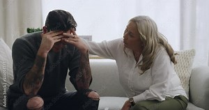 Man crying and being comforted by psychologist during therapy. Upset and anxious man with his head in his hands and sharing trauma story with mature therapist. Stressed and seeking mental health help