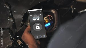 turning on bike using smart phone digital key app keyless security system,man uses smartphone mobile application to unlock and turn on motorbike