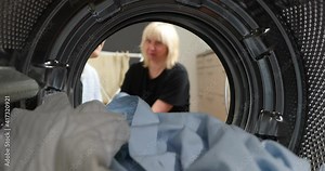 Women Housewife takes out laundry and a broken element the washing machine. Broken washing machine. Woman has problem with washing machine. View Looking Out From Inside Washing Machine