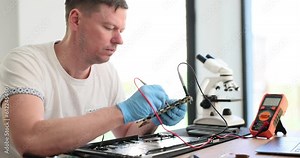 Master checks the condition of laptop circuit board with tester. Experienced engineer working with voltage detector for electronic equipment in service center