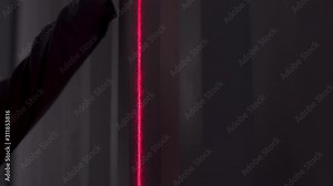 Professional worker using laser level measuring tool in dark room. Stock footage. Close up of red beam of laser level and man hands measuring the height of the wall with a construction roulette.