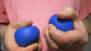 Closeup of a man’s hands holding and repeatedly squeezing two soft blue stress balls.