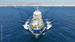 Aerial drone loop video of industrial liquified LPG gas tanker cruising near gas terminal