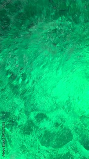 Close-up vertical footage of water bubbling in jacuzzi spa in swimming pool. Alluring green transparent water with air bubbles in a luxurious hot tub or jacuzzi.