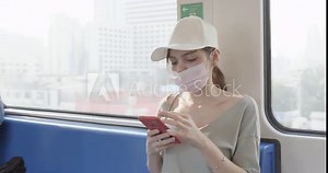 female tourist uses a cell phone while traveling on public transportation to the airport.