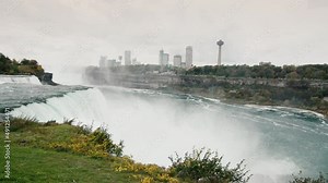 Pan shot: The mighty stream of water of Niagara Falls, in the distance you can see the Canadian coast