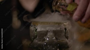 The cocktail is carefully poured into a skull-shaped glass, with colorful layers of ingredients creating a visually striking and intriguing presentation