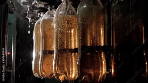 Manufacturing of carbonated, fizzy beverages, juices, soft drinks on factory. Production and bottling lemonade in plastic bottles on automatic conveyor line on industrial plant. Food industry concept.