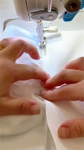 sewing the white fabric cloth using a silver metal needle tool on the electric sewing machine indoor