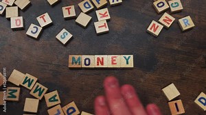 MONEY. Savings concept represented by little wooden wordplay letters arranged on a dark wooden table. Visible hands of an unrecognizable caucasian person. High quality 4k footage