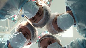 Surgical team bends over the patient