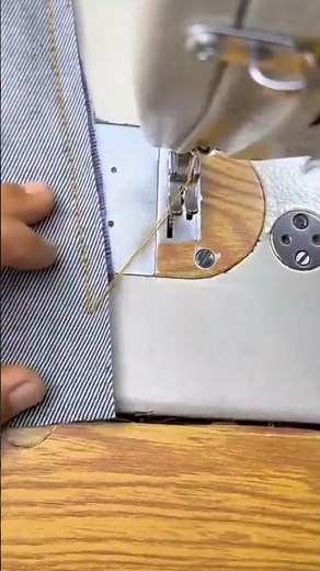 sewing a straight edge on a gray striped denim fabric surface using a manual lockstitch machine