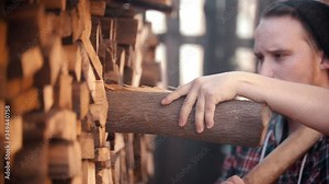 Young man woodcutter with ax puts in the log in the stand