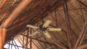 Big fan hanging from the ceiling spinning with a straw roof in the caribbean fan Stock Footage 4k
