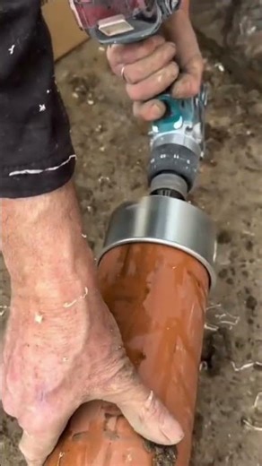 hole saw attachment on a power drill to precisely cut circular opening in a large PVC drainage pipe