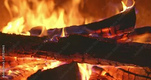 Close-up, flames of fire on a charred log. Log burns in a fireplace, a red flame. Cozy relaxing fireplace, firewood in a wood stove, red fire. 4k, ProRes