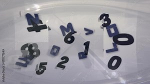 Magnetic stir bar spinning under container, forming vortex lifting numbers and letters for mixing