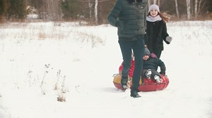 Family playing in the snow with an inflatable sled - Free Stock Video
